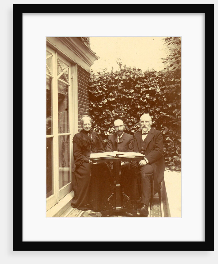 Two men and a woman sitting at home with a book on the table by Anonymous