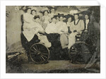 Group portrait of ten women and a man huddled in a carriage in a studio by Anonymous