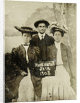 Portrait of a man and two women in front of a painted backdrop (tree, lake and mountains) and a sign that read 'Huntington FAIR 1905 by Anonymous