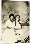 Portrait of two women sitting on a bench in front of a painted backdrop (chapel or church (?) In a lake), in the left part of the American flag by Anonymous