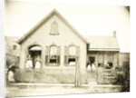 View of a wooden house with about nine people before or standing in doorways, United States by Anonymous