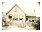 View of a wooden house with about nine people before or standing in doorways, United States by Anonymous