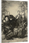Two men and two women standing and sitting in front of a painted backdrop (forest) by Anonymous