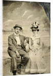 Portrait of a man and woman sitting in front of a painted backdrop (beach, sea and pier) by Anonymous