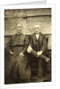 Portrait of an elderly man and woman sitting on a wooden wall or fence by Anonymous