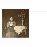 Female working at a table with tablecloth and flowers by Anonymous