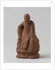Man figure with raised right leg on rocky pedestal. Red stoneware. by Anonymous