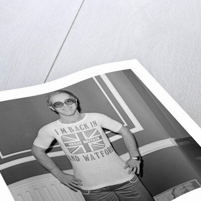 Elton John returns from America to announce that he is back in Britain for good. by Carl Bruin