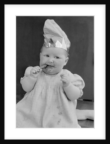 Baby wearing a party hat and eating a Cadbury chocolate finger by Staff