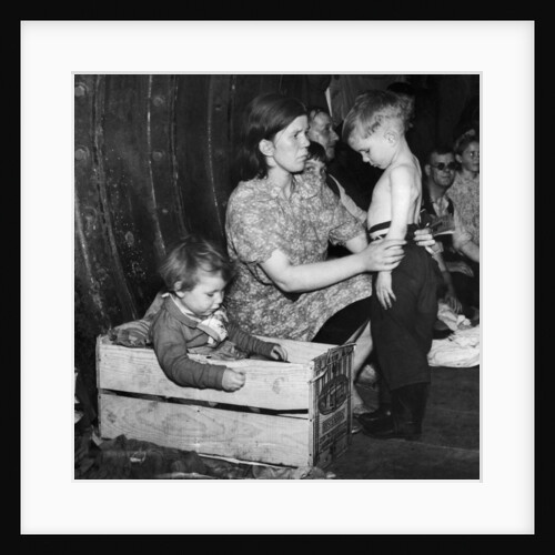 A mother tends to her young son in an underground bomb shelter during an air raid by Staff