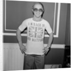 Elton John returns from America to announce that he is back in Britain for good. by Carl Bruin