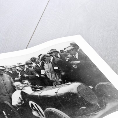 Gordon Taylor in a racing car surrounded by a crowd of men by Unknown