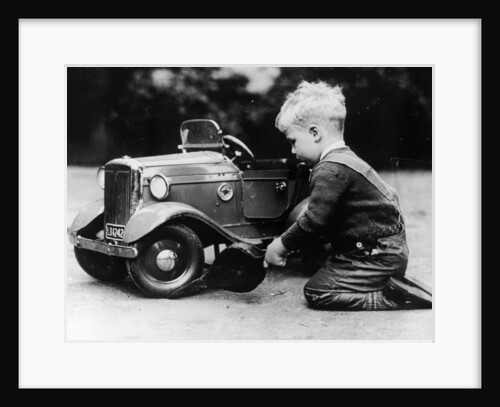 Michael Ware repairing a pedal car by Unknown