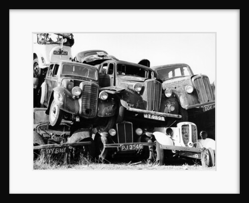 Old cars piled up in a scrapyard, Britain by Unknown