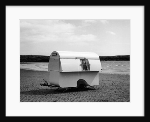 Woman smiling from the window of a trailer caravan on a beach, (c1960s?) by Unknown