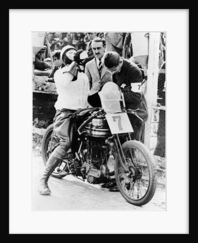 Van Horne taking a drink whilst on his Norton bike by Unknown