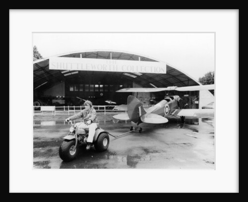 A Honda all terrain cycle pulling a vintage biplane by Anonymous