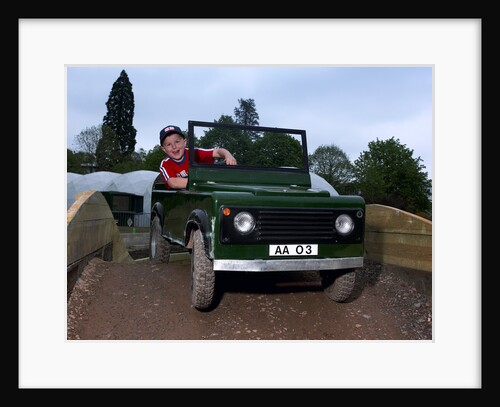 Child driving a toy Land Rover by Unknown