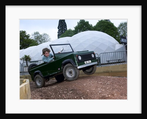 Child driving a toy Land Rover by Unknown