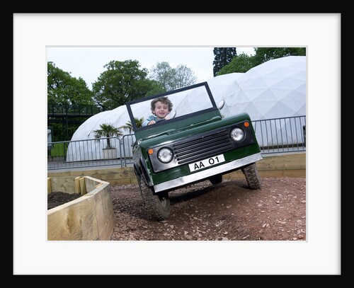 Child driving a toy Land Rover by Unknown