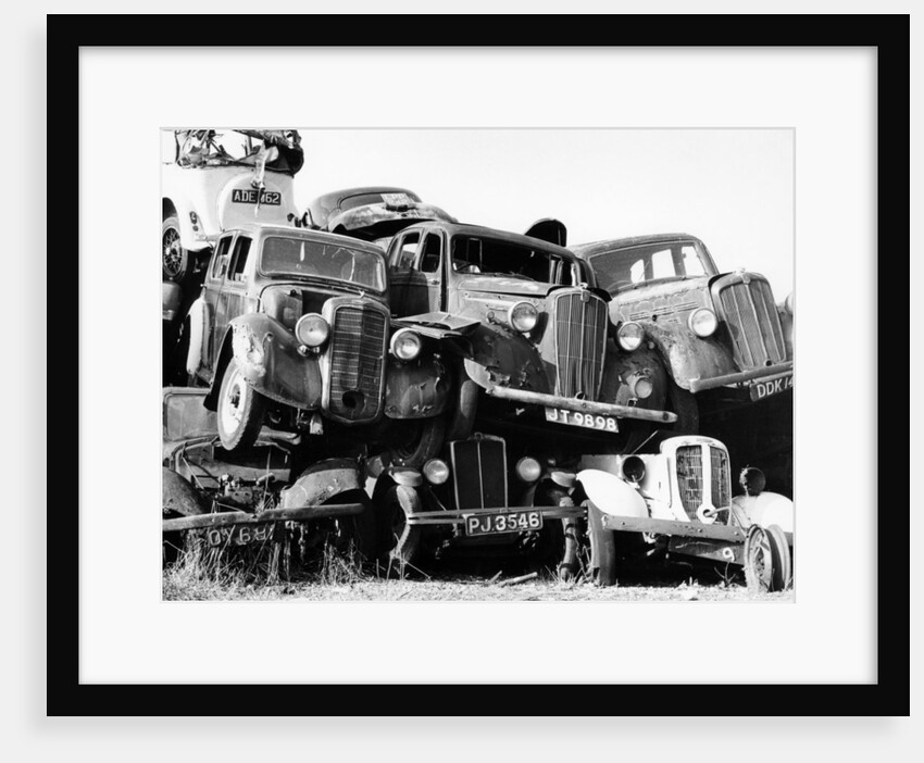 Old cars piled up in a scrapyard, Britain by Unknown