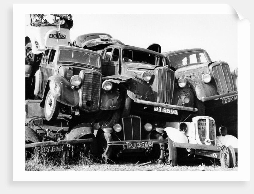 Old cars piled up in a scrapyard, Britain by Unknown