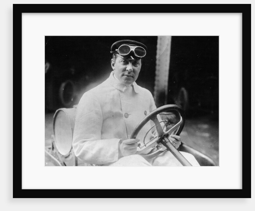 A man at the wheel of his car dressed in a driving coat and goggles by Unknown