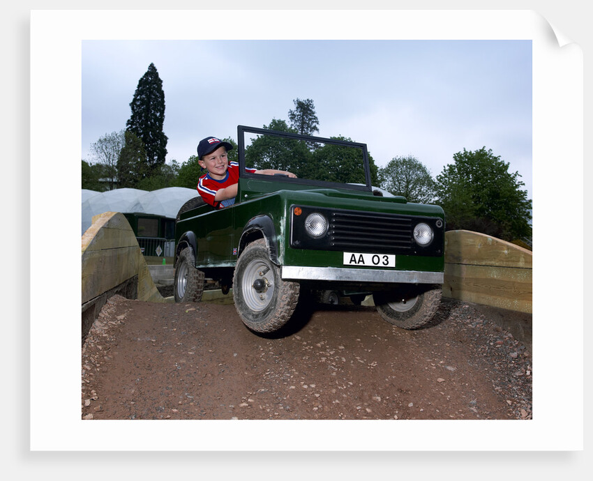 Child driving a toy Land Rover by Unknown