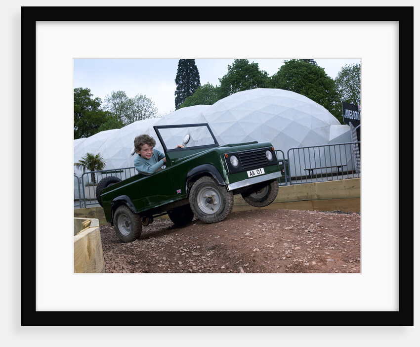 Child driving a toy Land Rover by Unknown