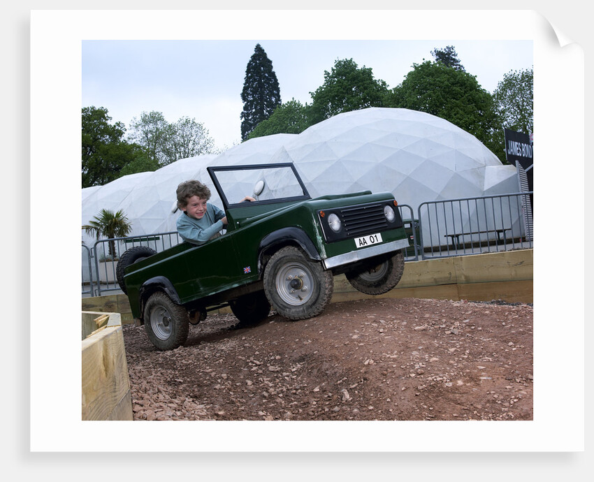 Child driving a toy Land Rover by Unknown