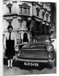 Female chauffeur standing by a 1964 Morris Oxford, 1964 by Unknown