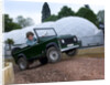 Child driving a toy Land Rover by Unknown