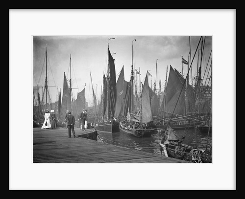 A view from the wooden quay at Lowestoft, Suffolk, looking across the trawl basin filled with a large number of sailing trawlers by Smiths Suitall Ltd.