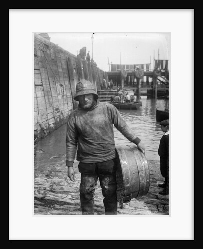 A Folkestone fisherman in smock and sou'wester carrying a tub for fish on the slipway by unknown