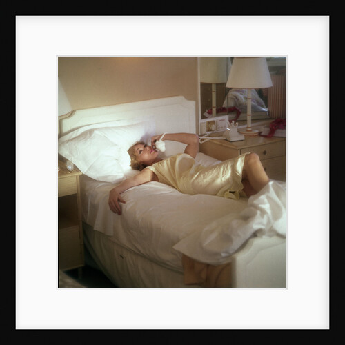 Modern convenience aboard a cruise liner: a female passenger reclines in bed whilst making a phone call; the ship and the conversation's content are unspecified by Marine Photo Service