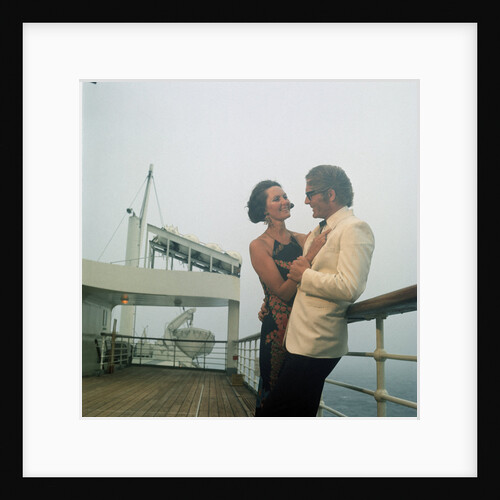 A misty evening offers amorous opportunities on deck for a romantic, smartly dressed, couple on a cruise ship by Marine Photo Service
