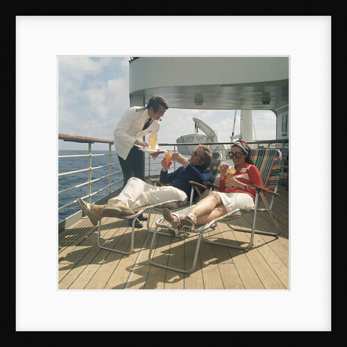 A ship's steward serves drinks to passengers on deck by Marine Photo Service