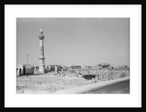 Minaret, stacked building stone and new buildings, Manama by Alan Villiers