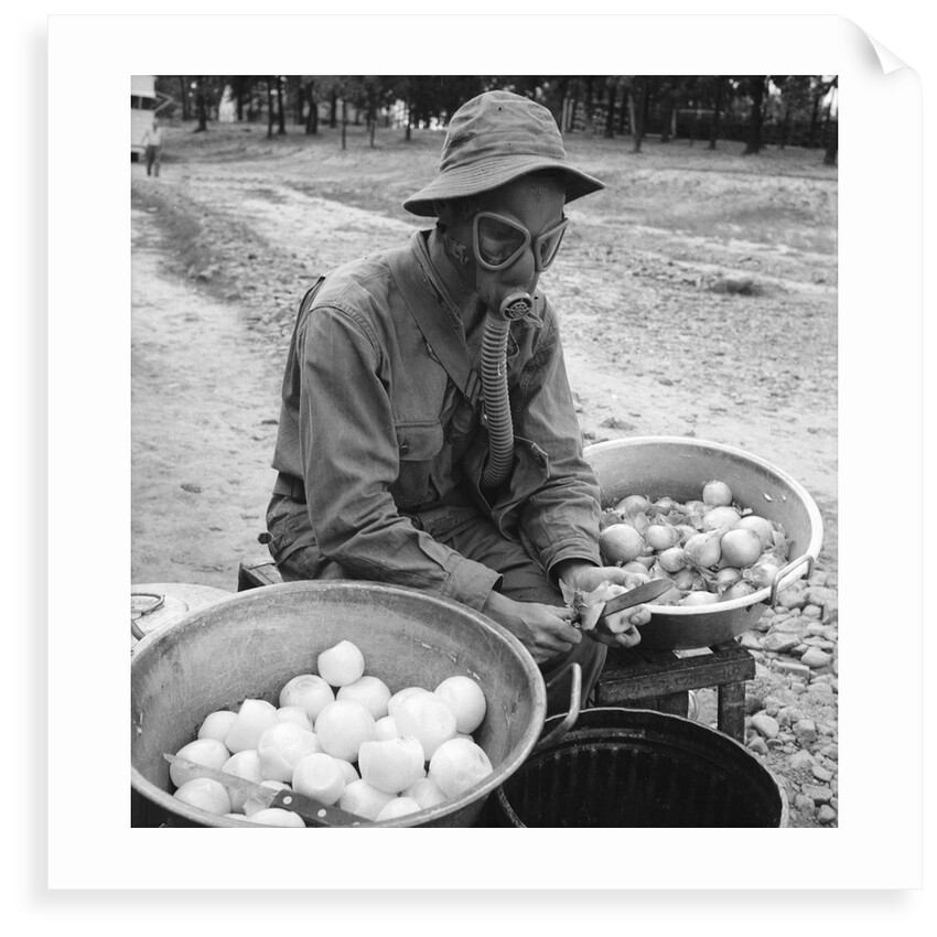 American soldier peeling onions while wearing a gas mask by Alan Villiers