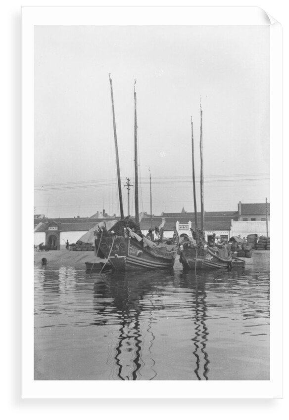A bow view of two Tsingtao fisher type junks moored stern-on to the shore at Tsingtao by David Watkin Waters