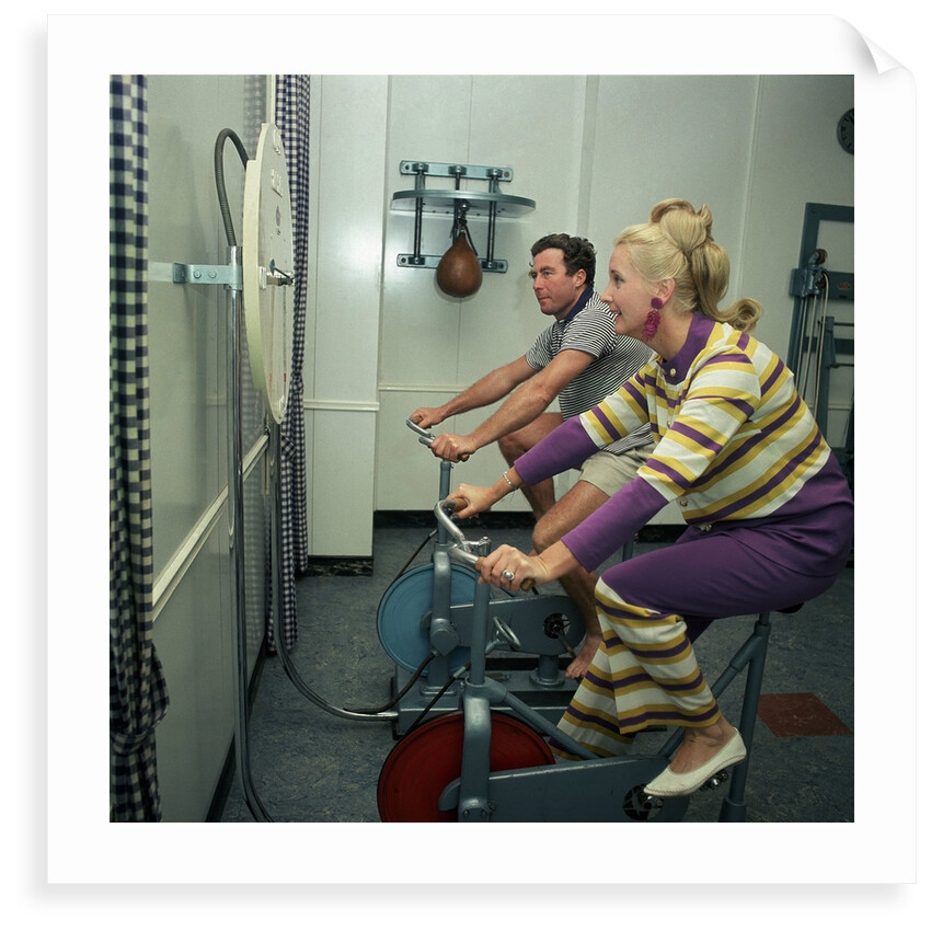After all the lunches and cocktail evenings, a little exercise is just the thing: two passengers use exercise bikes in the gym of an unspecified cruise liner by Marine Photo Service