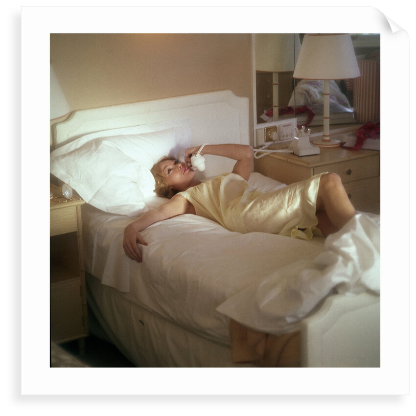 Modern convenience aboard a cruise liner: a female passenger reclines in bed whilst making a phone call; the ship and the conversation's content are unspecified by Marine Photo Service