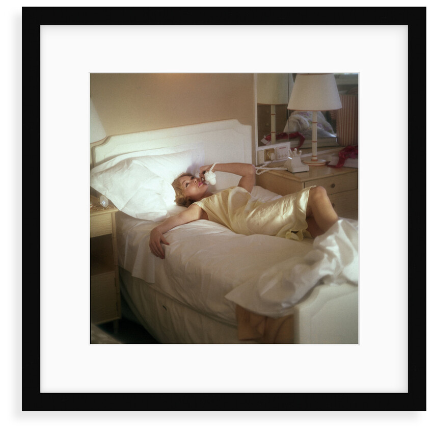Modern convenience aboard a cruise liner: a female passenger reclines in bed whilst making a phone call; the ship and the conversation's content are unspecified by Marine Photo Service