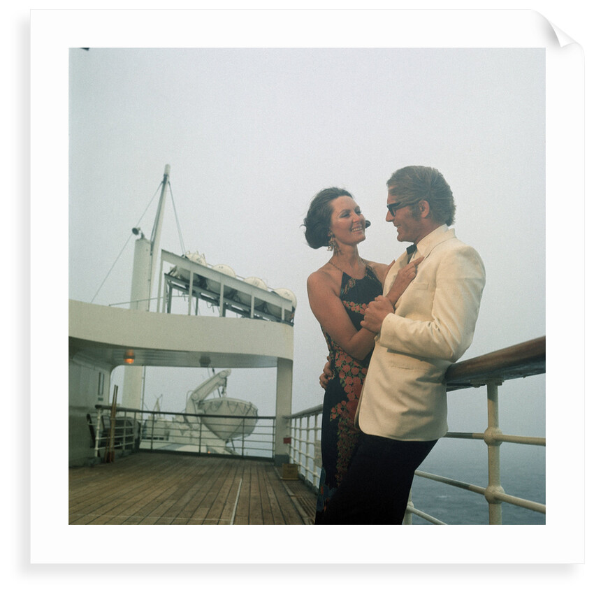 A misty evening offers amorous opportunities on deck for a romantic, smartly dressed, couple on a cruise ship by Marine Photo Service
