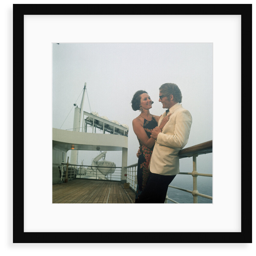 A misty evening offers amorous opportunities on deck for a romantic, smartly dressed, couple on a cruise ship by Marine Photo Service