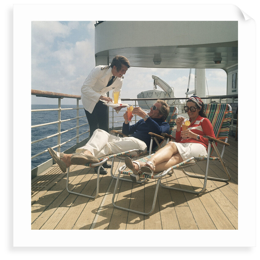 A ship's steward serves drinks to passengers on deck by Marine Photo Service