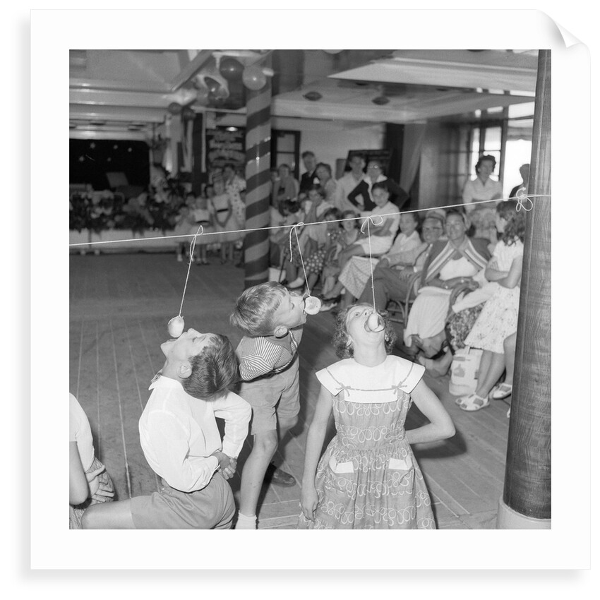 Three children in the "Apple Eating" contest, possibly in the ballroom of the 'Chusan' (1950) by Marine Photo Service