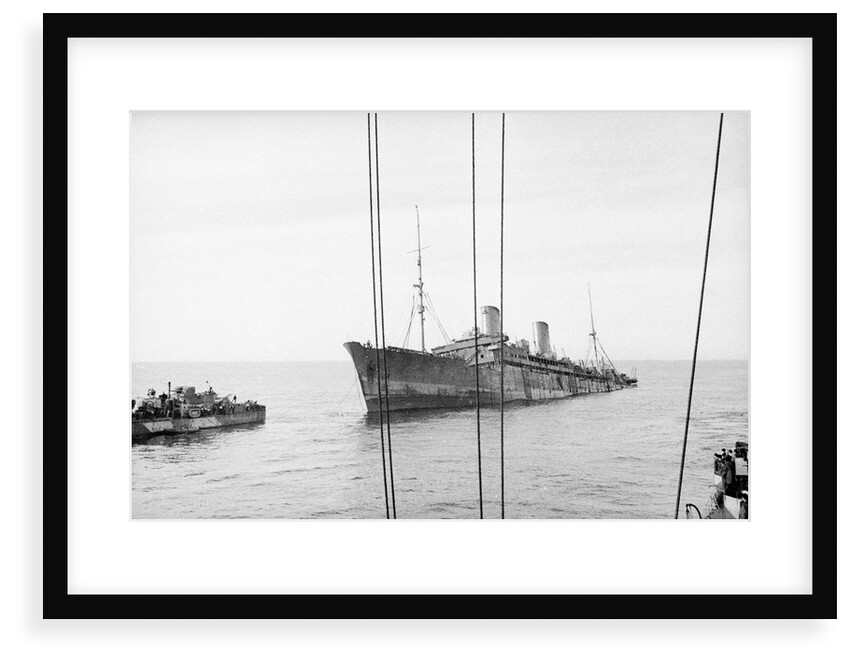 Photograph of 'Windsor Castle' sinking in 1943. Port bow view well down by the stern with the escort destroyer 'Farndale' (1940) near the bow. by Lt EJ Manners