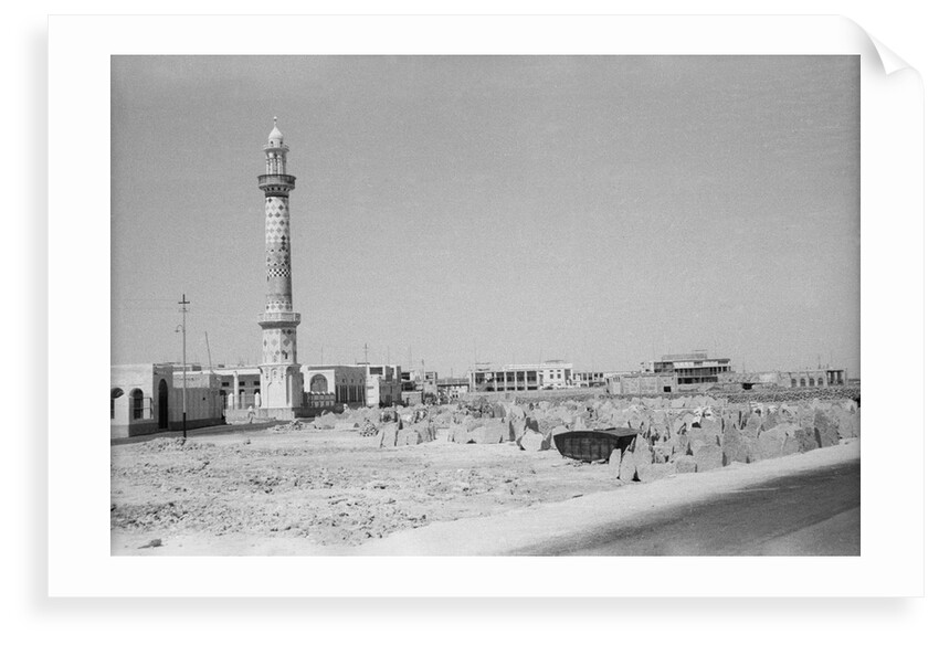 Minaret, stacked building stone and new buildings, Manama by Alan Villiers