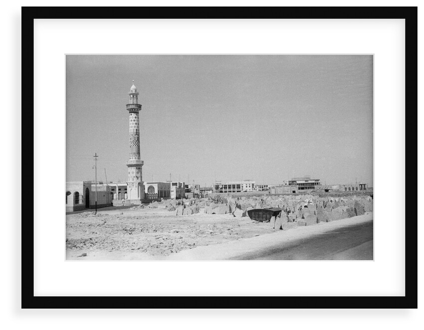 Minaret, stacked building stone and new buildings, Manama by Alan Villiers